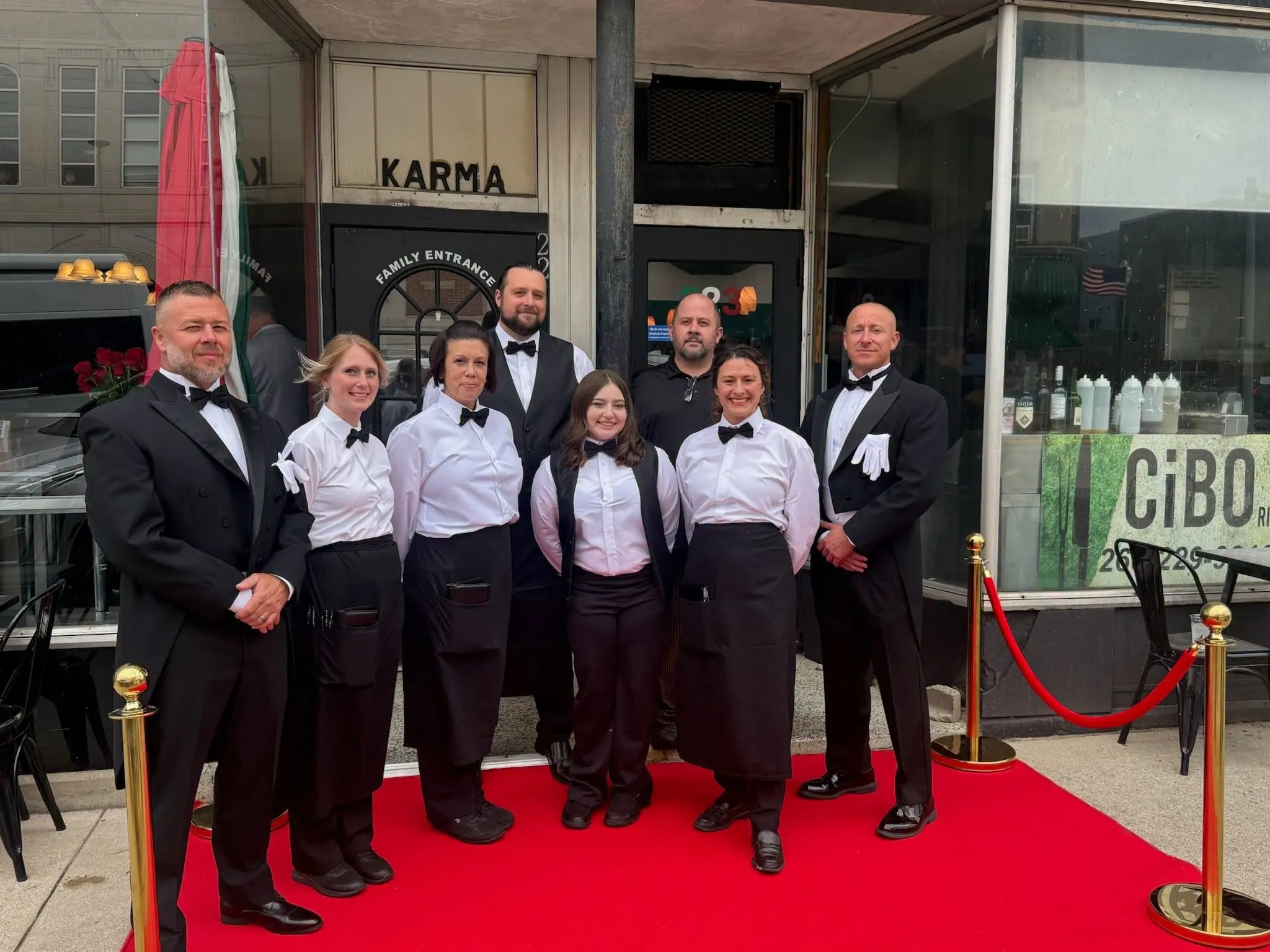 The CiBO staff in tuxedos and white shirts on a red carpet outside the restaurant for a dinner night.