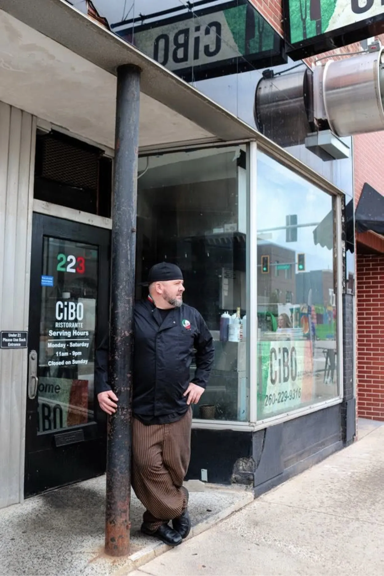 Wes Davison in his chef's coat, leaning on the post outside CiBO Ristorante on Van Buren Street.